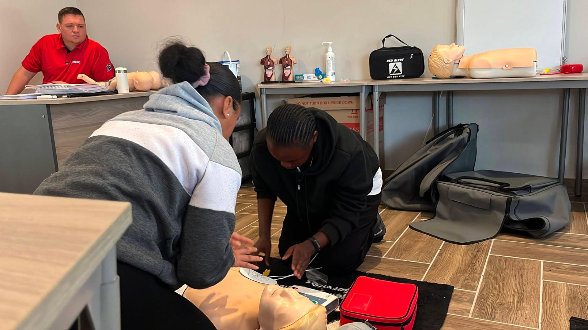 Learners practising CPR and defibrillator use on a training manikin