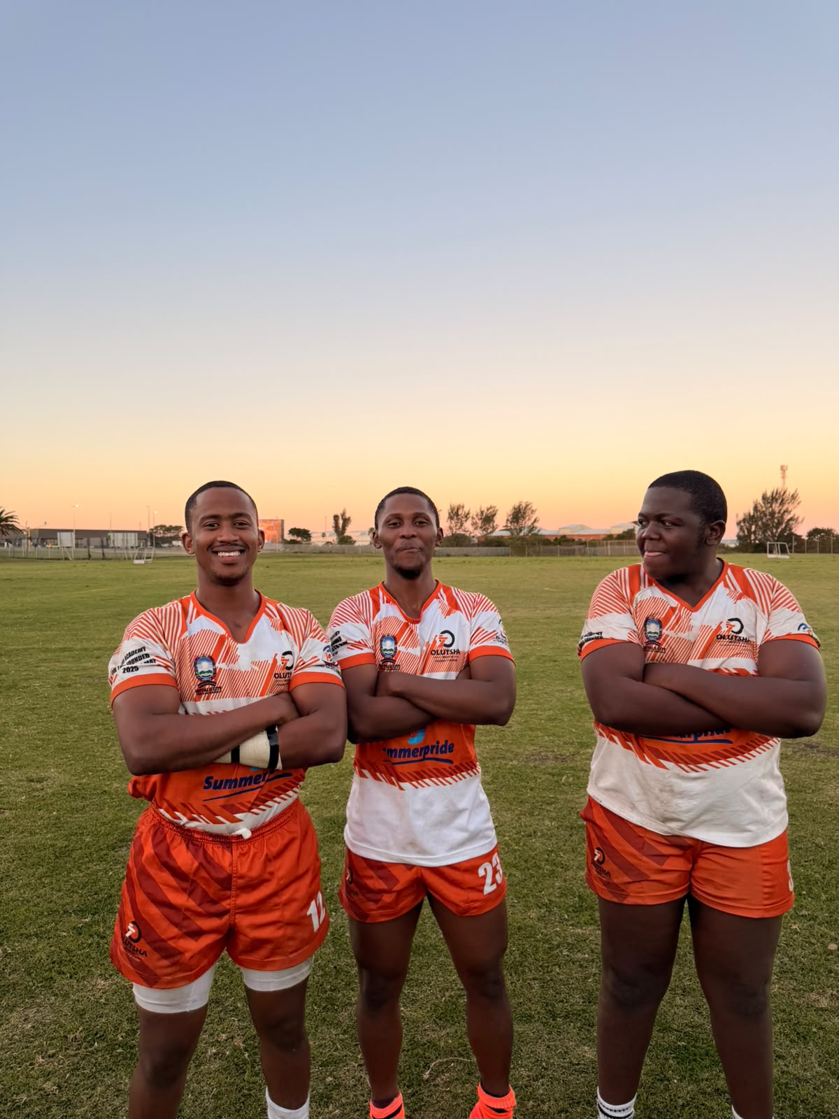 Three Olutsha players in the 2026 Summerpride kit at sunset